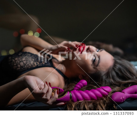 Beautiful brunette in lace lingerie holds pink dildo.  131337093