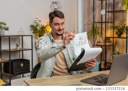 Caucasian freelancer accountant working with financial graph documents using laptop at table desk 131337216