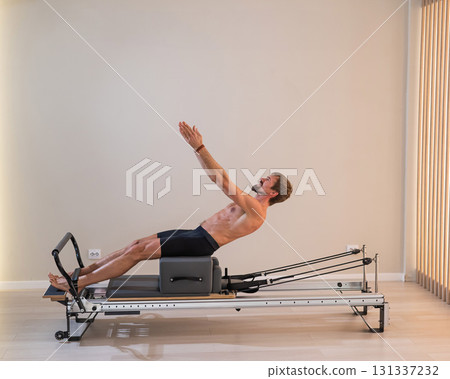 A man doing Pilates on a reformer. A man doing Pilates on a reformer. 131337232