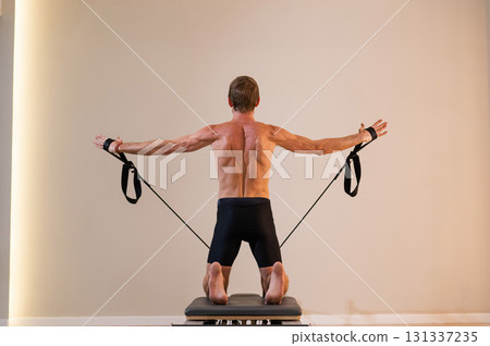 A man doing Pilates on a reformer.  131337235