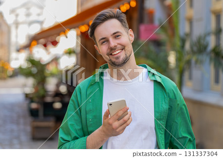 Man using smartphone typing text messages browsing internet, finishing work, looking at camera 131337304