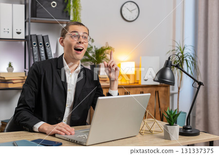 Happy young businessman in formal suit thinking and using laptop computer at home office desk Happy young businessman in formal suit thinking and using laptop computer at home office desk 131337375