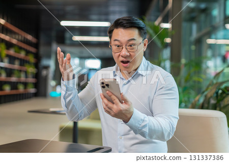 Happy amazed businessman using smartphone shocked by sudden victory lottery win in office lobby Happy amazed businessman using smartphone shocked by sudden victory lottery win in office lobby 131337386