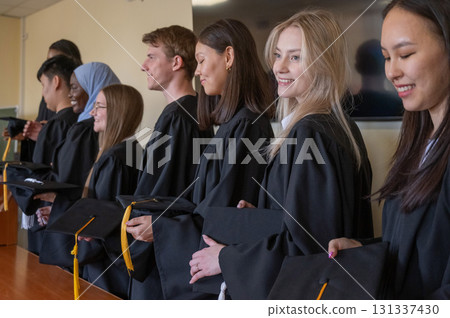 Young multinational people in graduation gowns stand at the lectern. Young multinational people in graduation gowns stand at the lectern. 131337430