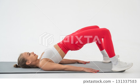 Young woman doing glute bridge on white background. 131337583