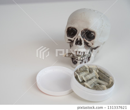 Skull Chewing Tobacco on a White Table. 131337621