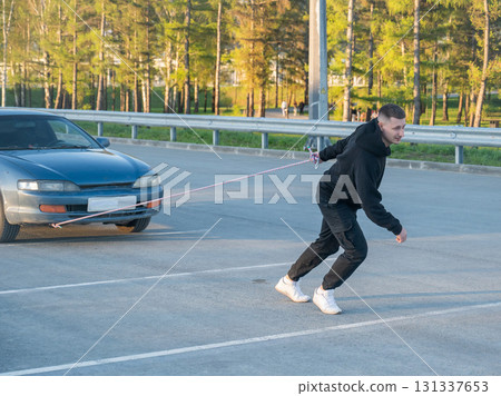Caucasian man pulling a car with a rope.  131337653