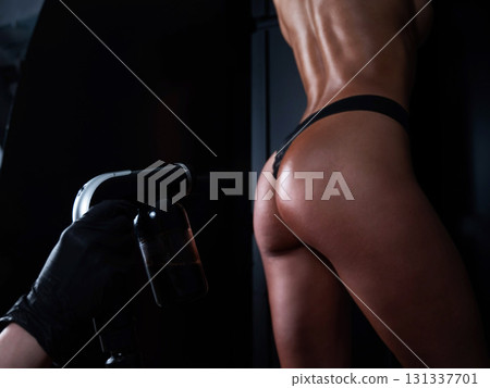 The master applies tinting paint on the back of a woman. Instant tanning treatment. The master applies tinting paint on the back of a woman. Instant tanning treatment. 131337701