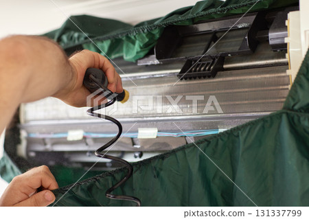 male hand of worker from the cleaning service cleans the air conditioner by spraying water, close-up male hand of worker from the cleaning service cleans the air conditioner by spraying water, close-up 131337799