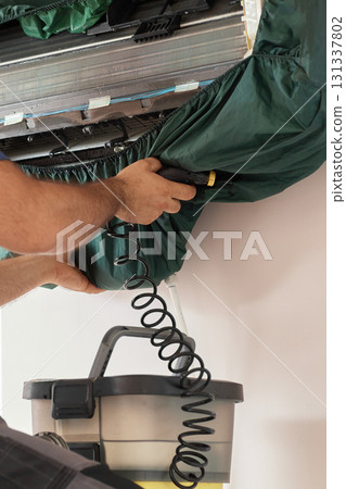 male hand of worker from the cleaning service cleans the air conditioner by spraying water, close-up male hand of worker from the cleaning service cleans the air conditioner by spraying water, close-up 131337802