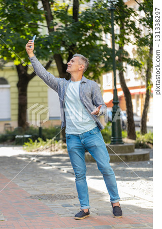 Mature male tourist trying to catch a communication signal and Internet on smartphone in city street 131338297