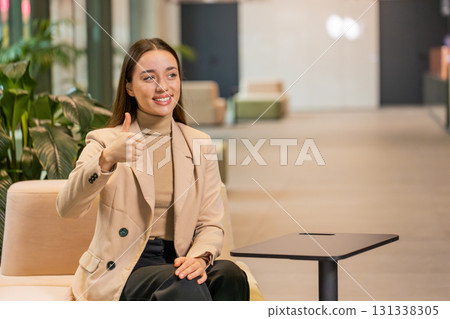 Portrait of smiling Caucasian young businesswoman girl in formal showing thumb up in hotel lobby Portrait of smiling Caucasian young businesswoman girl in formal showing thumb up in hotel lobby 131338305