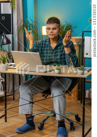 Indian man working on laptop eyes closed meditating concentrated thoughts taking a break relaxing Indian man working on laptop eyes closed meditating concentrated thoughts taking a break relaxing 131338310