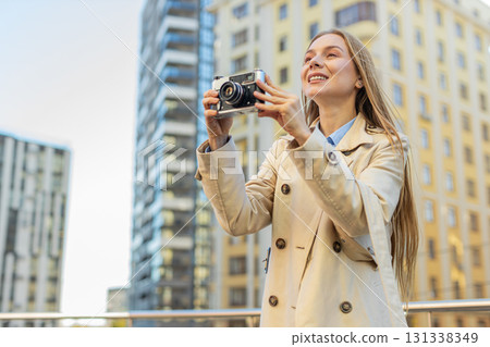 Happy mature woman tourist exploring city making pictures on retro vintage camera on city street Happy mature woman tourist exploring city making pictures on retro vintage camera on city street 131338349