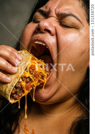 Overweight woman eating a large burrito with dripping cheese sauce. 131338720