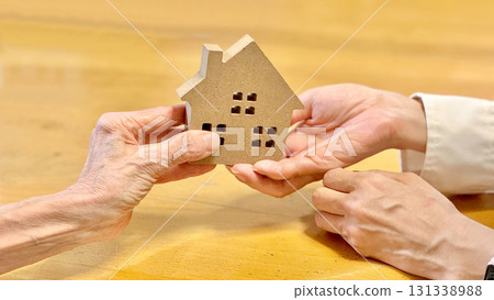 Elderly woman handing household items to another woman_ocher background Elderly woman handing household items to another woman_ocher background 131338988