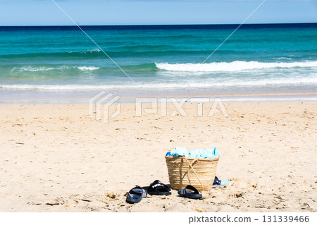 A bag rests on the white sand of a deep blue and emerald green coastline on Fuerteventura, Canary Islands 131339466