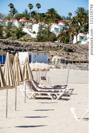在富埃特文圖拉島藍天和明媚的陽光下，沙灘上排列著沙灘床和遮陽傘 131339748