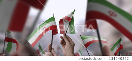 Iran flags in their hands on a blurred urban background 131340252