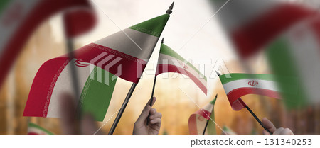 Iran flags in their hands on a blurred urban background Iran flags in their hands on a blurred urban background 131340253