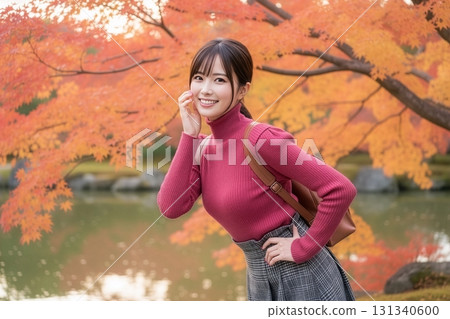 Smiling woman wearing a pink turtleneck sweater with autumn leaves in the background 131340600
