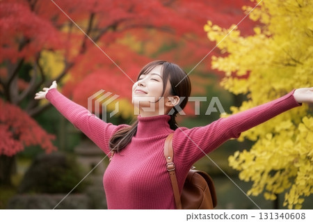 身穿粉紅色高領毛衣、微笑的女人，背景是秋葉 131340608