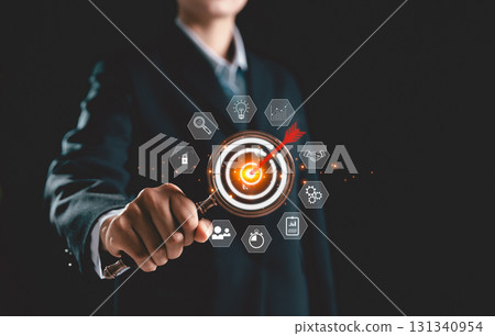 Businesswoman uses magnifying glass to focus on target board icon, symbolizing business concept of strategic planning, goal achievement, and innovation, key drivers of success in modern enterprises. Businesswoman uses magnifying glass to focus on target board icon, symbolizing business concept of strategic planning, goal achievement, and innovation, key drivers of success in modern enterprises. 131340954