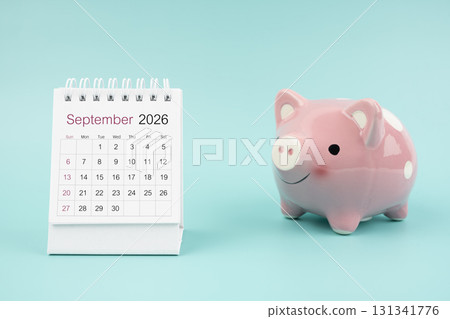 September 2026 Desk calendar and pink piggy bank on blue background. 131341776