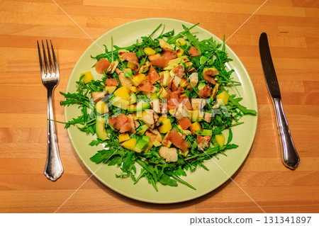 Fresh healthy salad with mango, avocado, salmon, arugula and croutons on wooden table 131341897