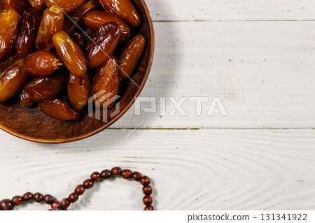 Dates fruit and rosary on white wooden table. Top view 131341922