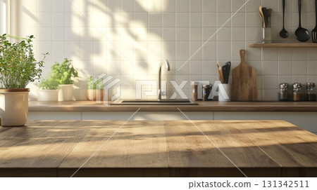 Sunlight illuminates a spacious kitchen with a wooden table in the foreground, potted herbs, and various kitchen utensils, creating a warm and inviting atmosphere 131342511