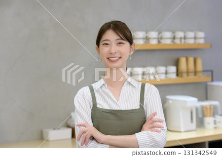 Female staff with arms crossed at a cafe Female staff with arms crossed at a cafe 131342549