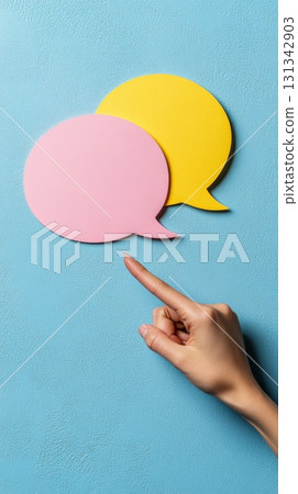 Hand pointing its index finger to two overlapping speech bubbles, one pink and one yellow, suggesting a question or a doubt in a communication process 131342903