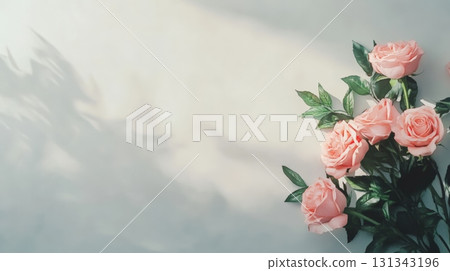 Bouquet of pink roses with green leaves lying on white table with shadows of plant creating romantic atmosphere, perfect for valentine's day, mother's day or spring celebrations Bouquet of pink roses with green leaves lying on white table with shadows of plant creating romantic atmosphere, perfect for valentine's day, mother's day or spring celebrations 131343196