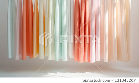 Multiple pastel colored fabrics are hanging in a fashion designer's studio, creating a gradient of soft hues and inspiring creativity for new clothing designs 131343207