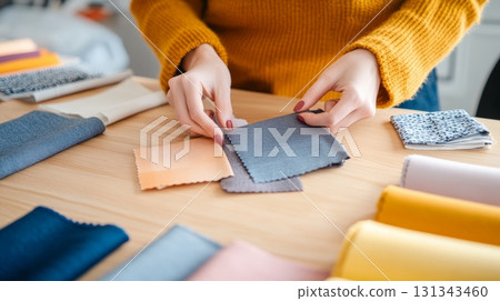 Fashion designer selecting fabric samples for new clothing collection, working at a desk with various colorful textiles and materials, creating stylish and trendy garments Fashion designer selecting fabric samples for new clothing collection, working at a desk with various colorful textiles and materials, creating stylish and trendy garments 131343460