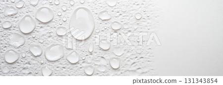 Crystal clear water droplets rest on a textured white surface. Creating a visually appealing contrast and showcasing the hydrophobic properties of the material. Suitable for backgrounds and textures 131343854
