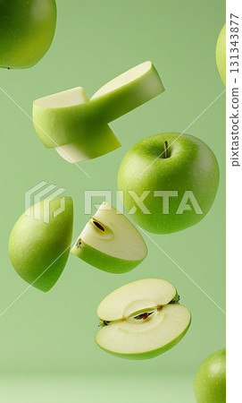 Whole and sliced green apples levitating against a plain green background, creating a vibrant and dynamic visual composition full of freshness and energy 131343877
