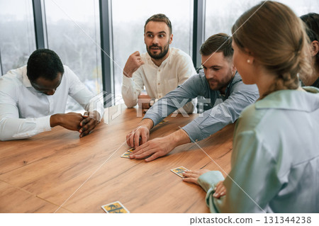 Playing card game. Team of office workers are together indoors 131344238