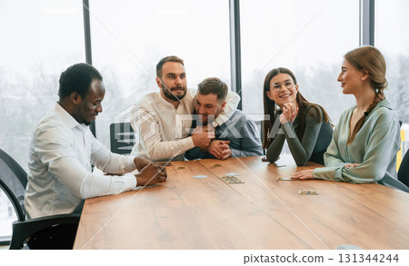 Going crazy, playing card game, having fun. Team of office workers are together indoors 131344244