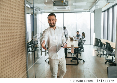Man is with documents, front view. Team of office workers are together indoors Man is with documents, front view. Team of office workers are together indoors 131344476