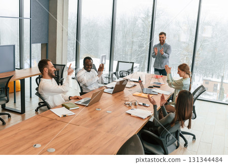 Sitting by the table. Team of office workers are together indoors Sitting by the table. Team of office workers are together indoors 131344484
