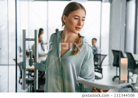 Female manager is with documents. Team of office workers are together indoors Female manager is with documents. Team of office workers are together indoors 131344506