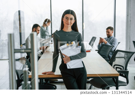 In front of colleagues. Woman is standing. Team of office workers are together indoors In front of colleagues. Woman is standing. Team of office workers are together indoors 131344514