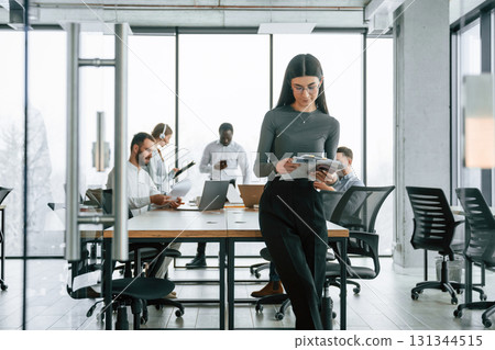 In front of colleagues. Woman is standing. Team of office workers are together indoors In front of colleagues. Woman is standing. Team of office workers are together indoors 131344515