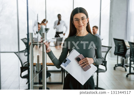 Young woman in glasses, portrait. Team of office workers are together indoors Young woman in glasses, portrait. Team of office workers are together indoors 131344517