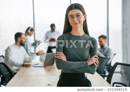 Young woman in glasses, portrait. Team of office workers are together indoors Young woman in glasses, portrait. Team of office workers are together indoors 131344519