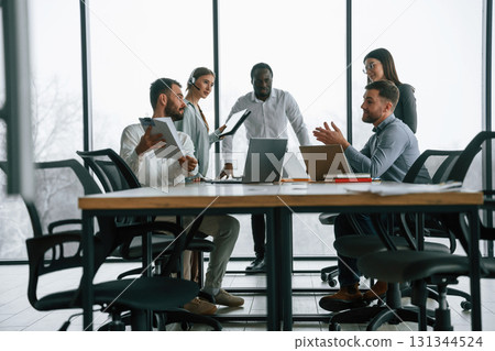 Against big panoramic windows. Team of office workers are together indoors Against big panoramic windows. Team of office workers are together indoors 131344524