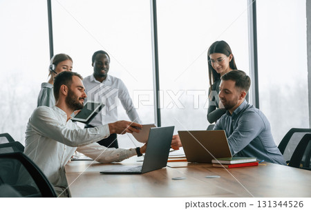 Against big panoramic windows. Team of office workers are together indoors 131344526