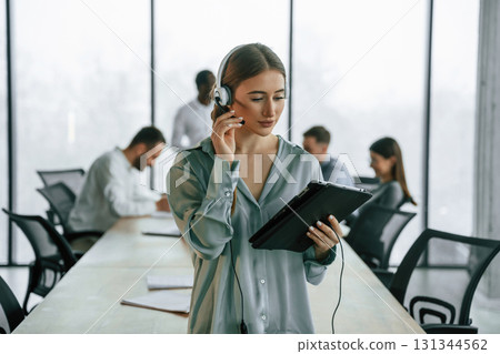 Call center. Woman in headphones. Team of office workers are together indoors 131344562